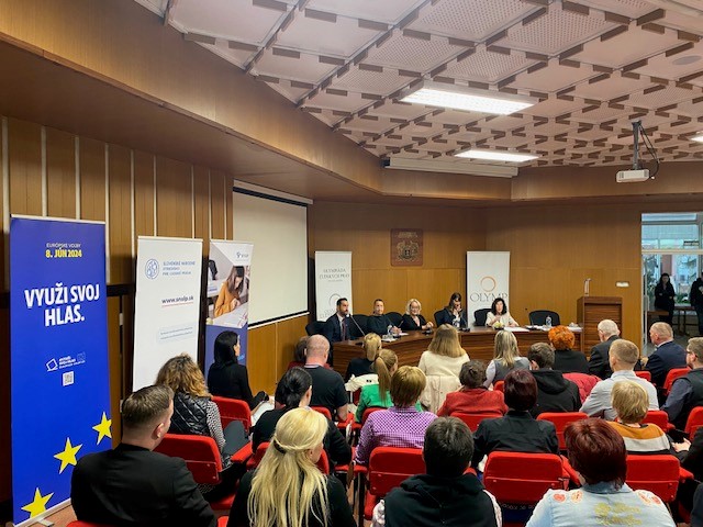 Na obrázku sa nachádzajú ľudia, sediaci pred komisiou a rokujú.