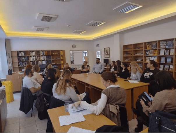 Fotka zo vzdelávacieho stretnutia. Ľudia sedia v školiacej miestnosti a diskutujú.
