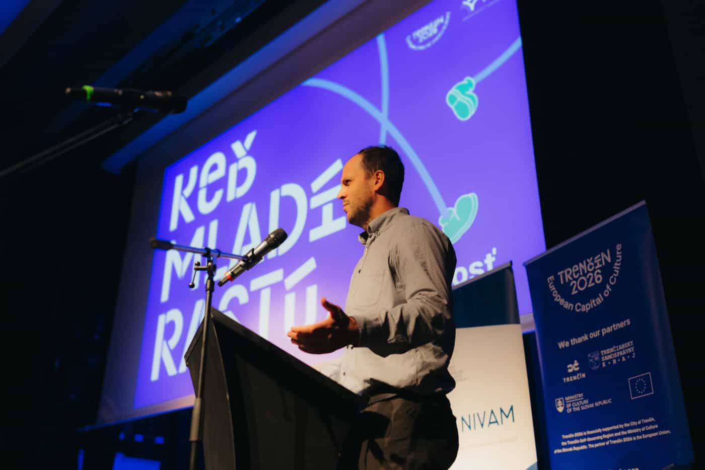 Riaditeľ OPNVŠŠ NIVaM stojí pri rečníckom pulte konferencie