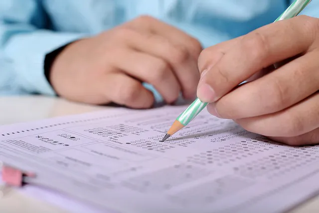 Záber na ruky žiaka vypĺňajúceho test ceruzkou.