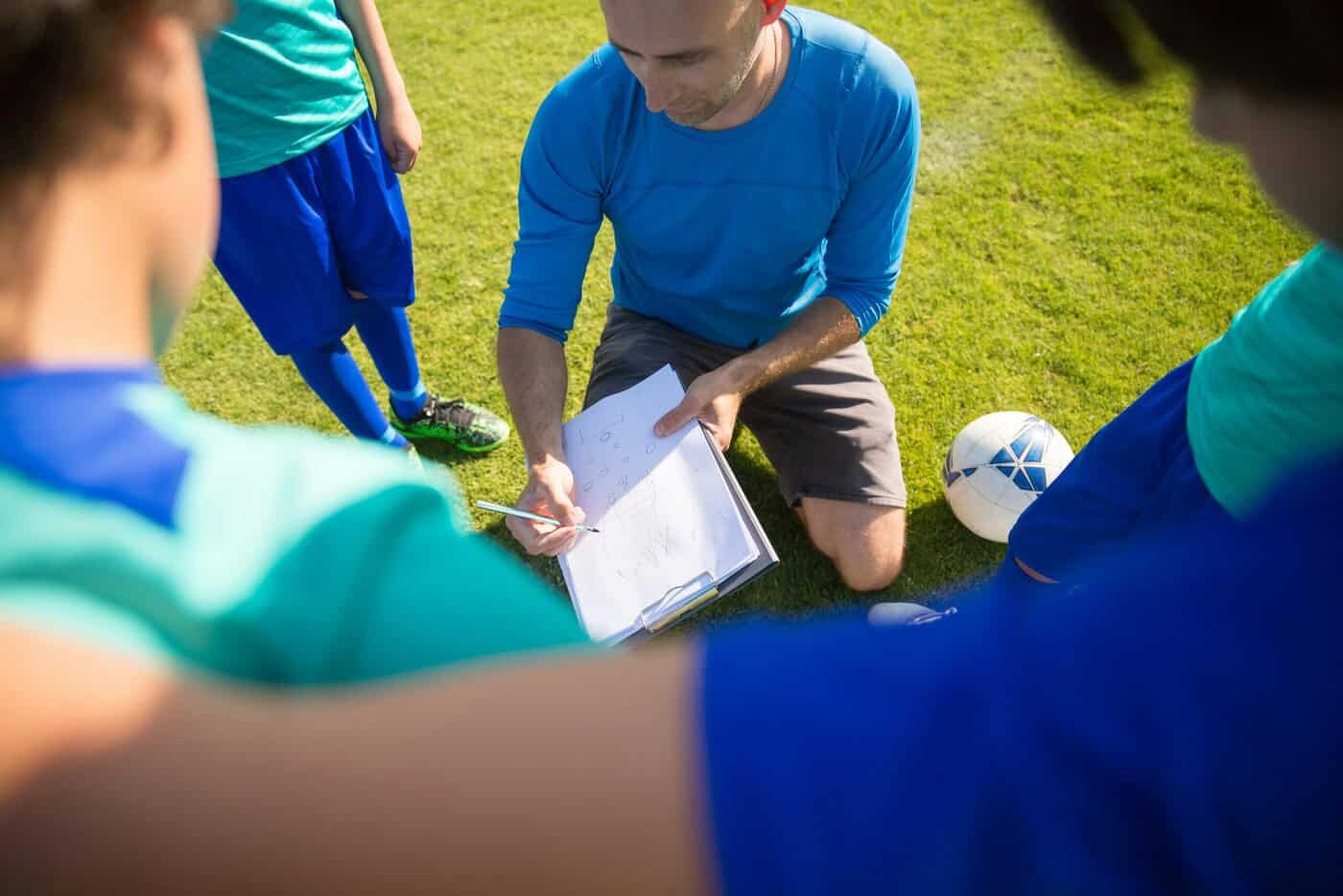 Na obrázku sa nachádza futbalový tréner s jeho družstvom