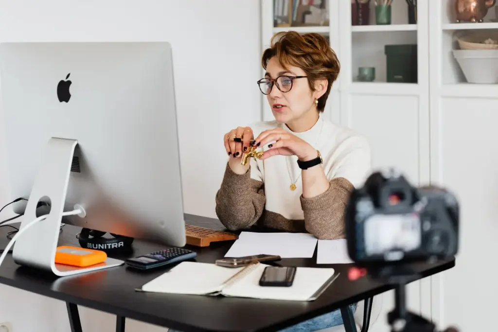 Na fotke žena za písacím stolom diskutuje cez online hovor.